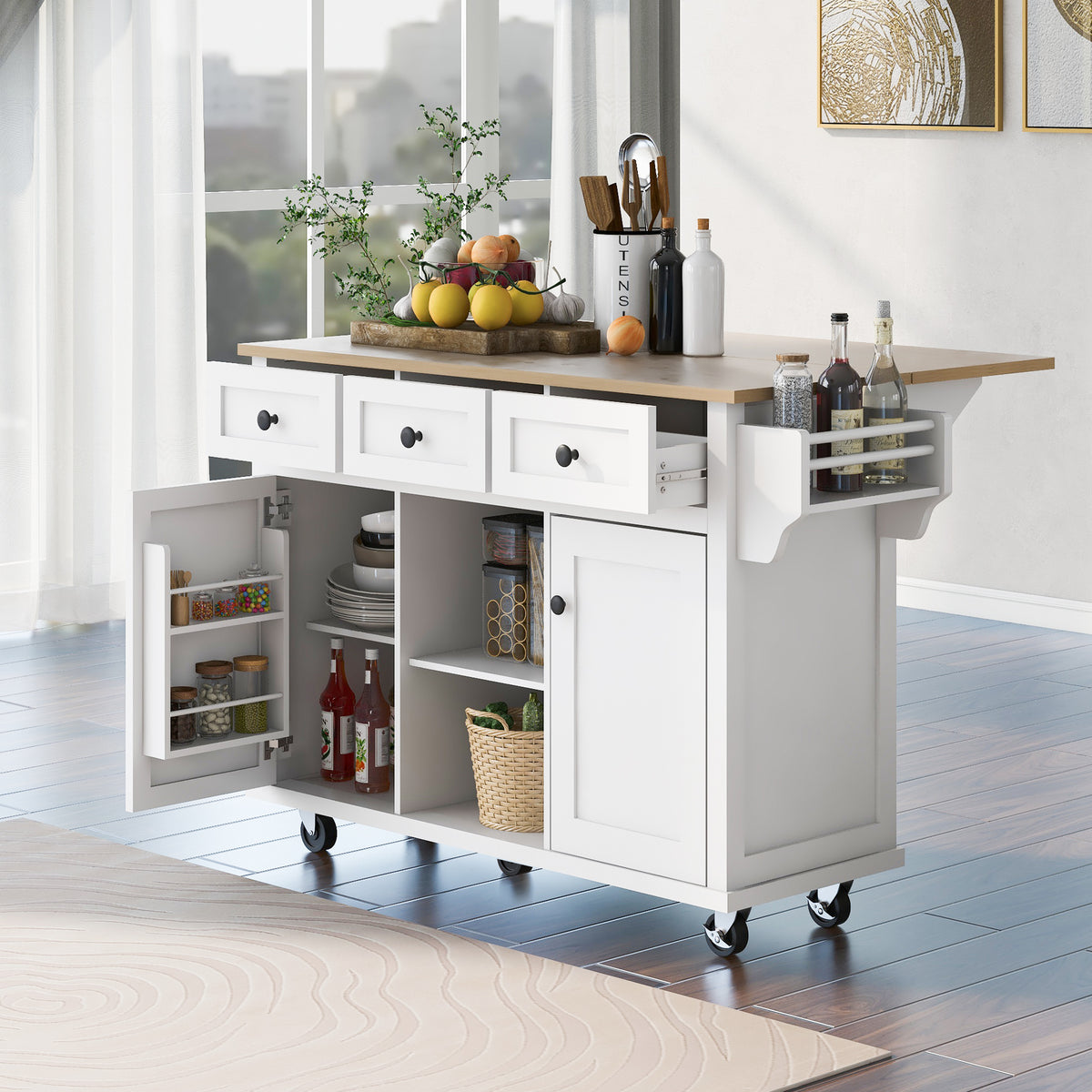 Angled view of a white kitchen island with open drawers, one open cabinet door, and a stocked side rack.