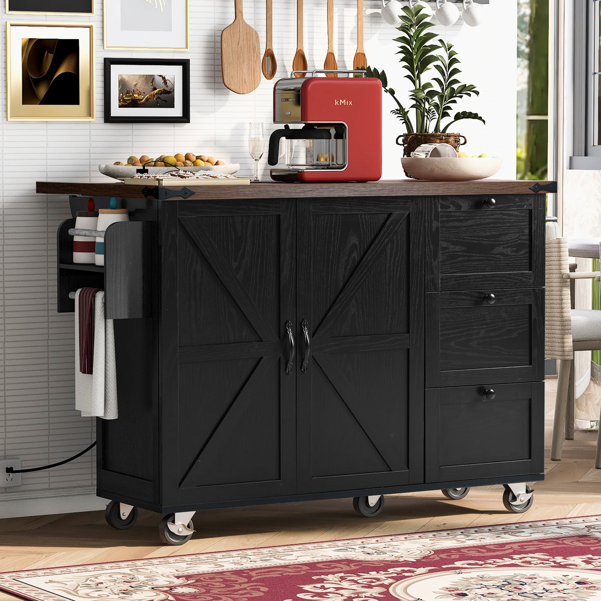 Black rolling kitchen island with cross-braced cabinet doors, three drawers, and a brown countertop beneath hanging utensils.