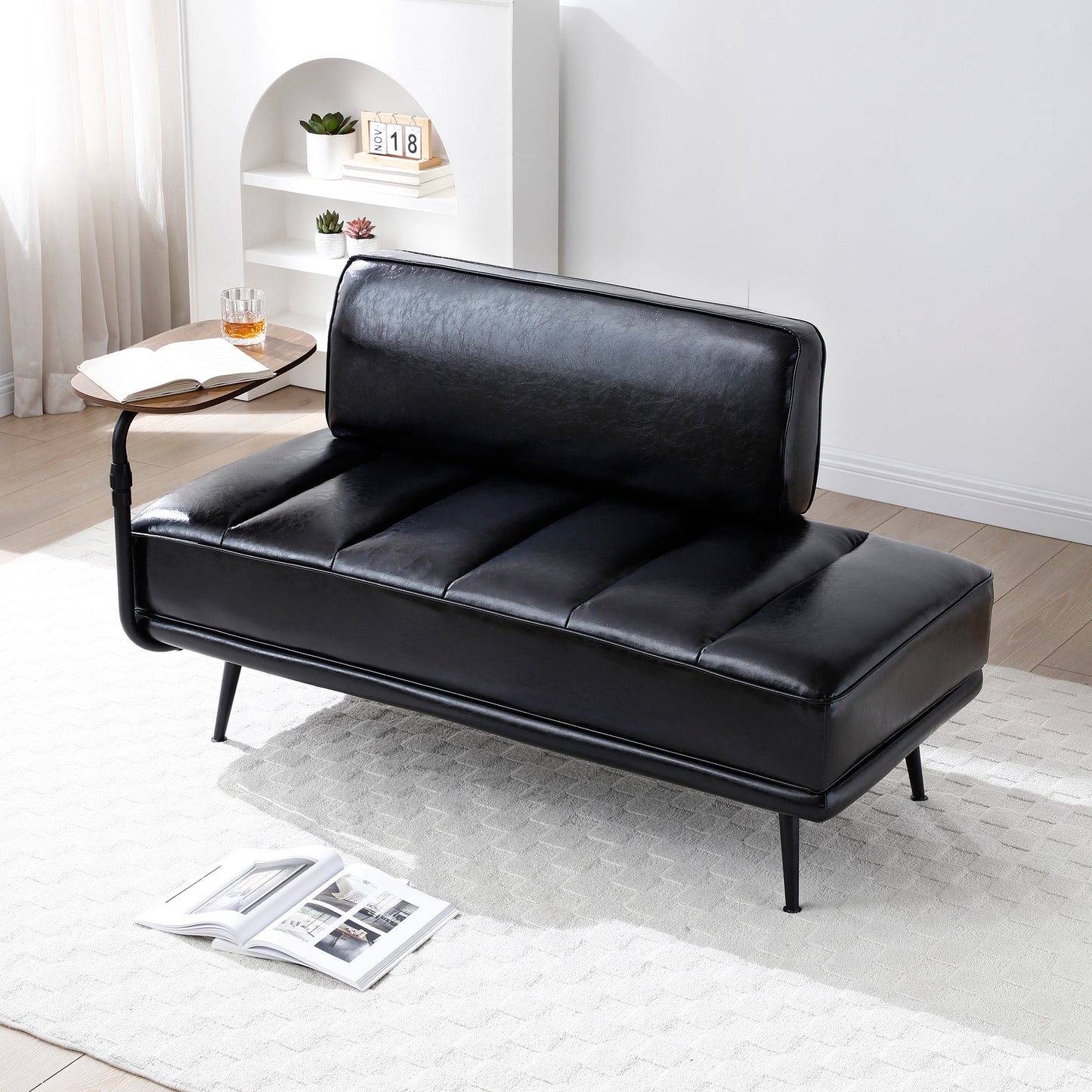 Black leather sofa in a living room setting with a white rug and minimal decor.