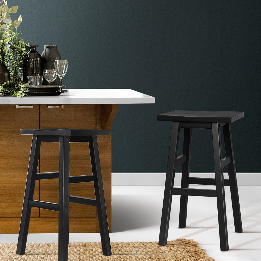 Dining area with a wooden table, white countertop, and two black stools against a dark gray wall.