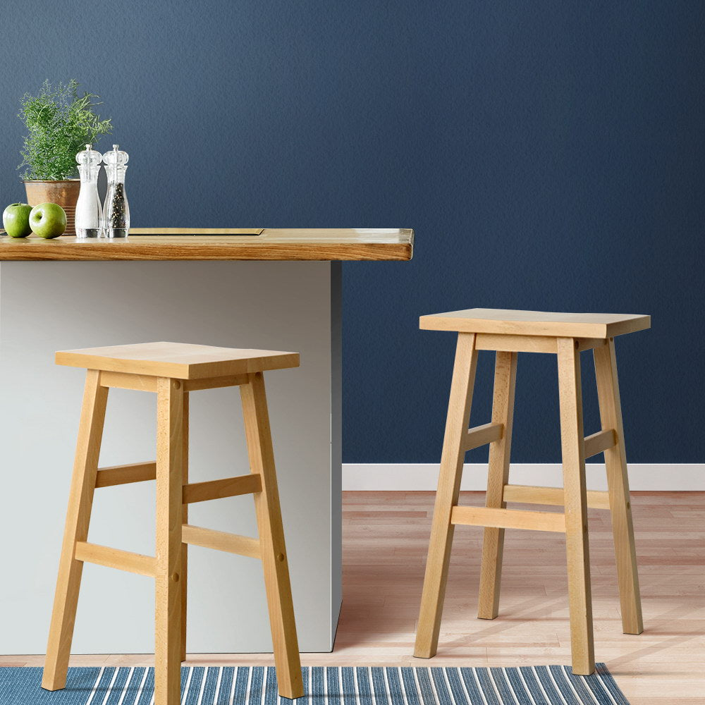Wooden bar stools in front of a small wooden table against a blue wall.