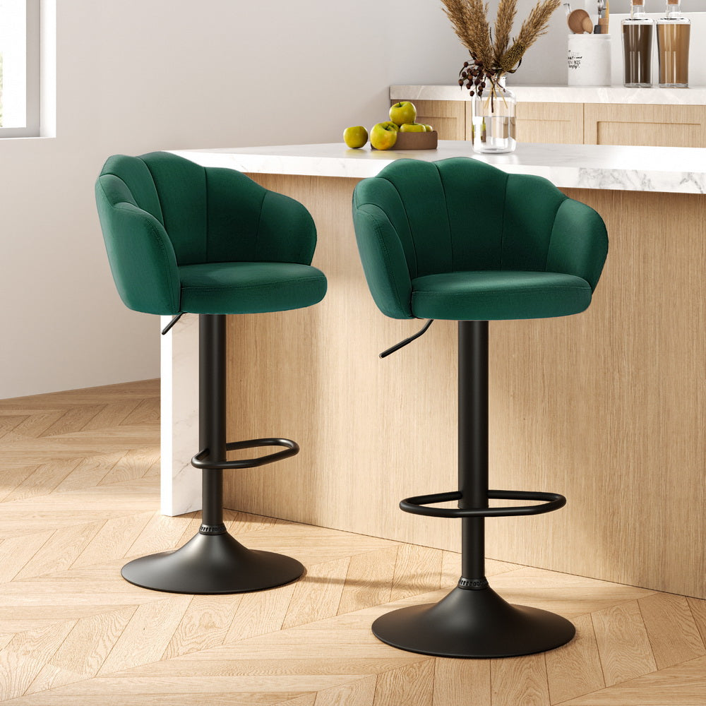Two green bar stools with black bases in a kitchen setting.
