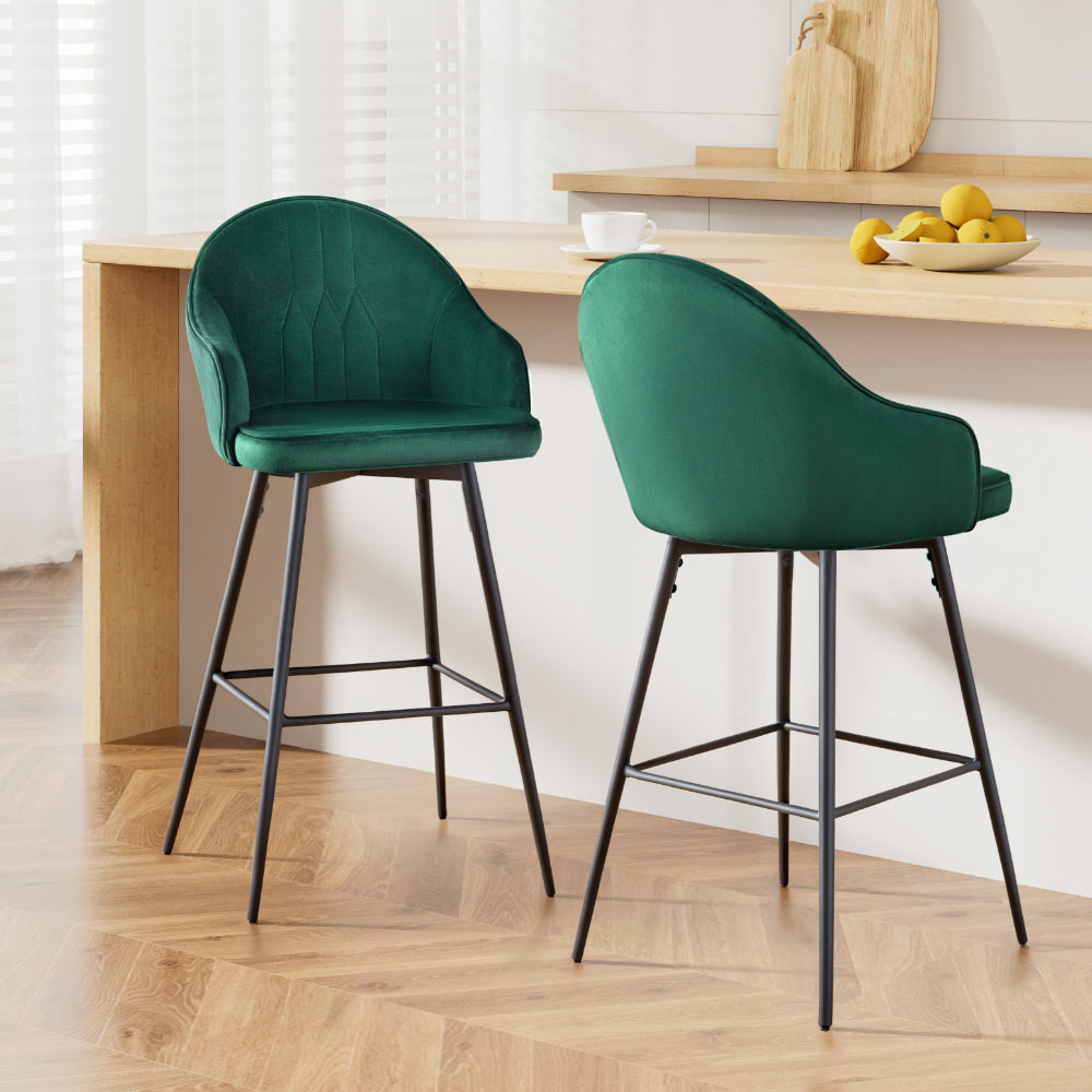 Two green bar stools with black legs in a kitchen setting.