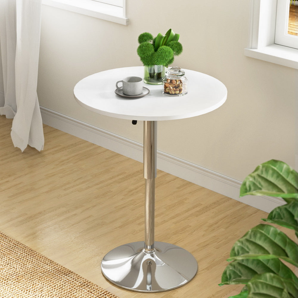 White round table with a silver base in a room with plants and a window.
