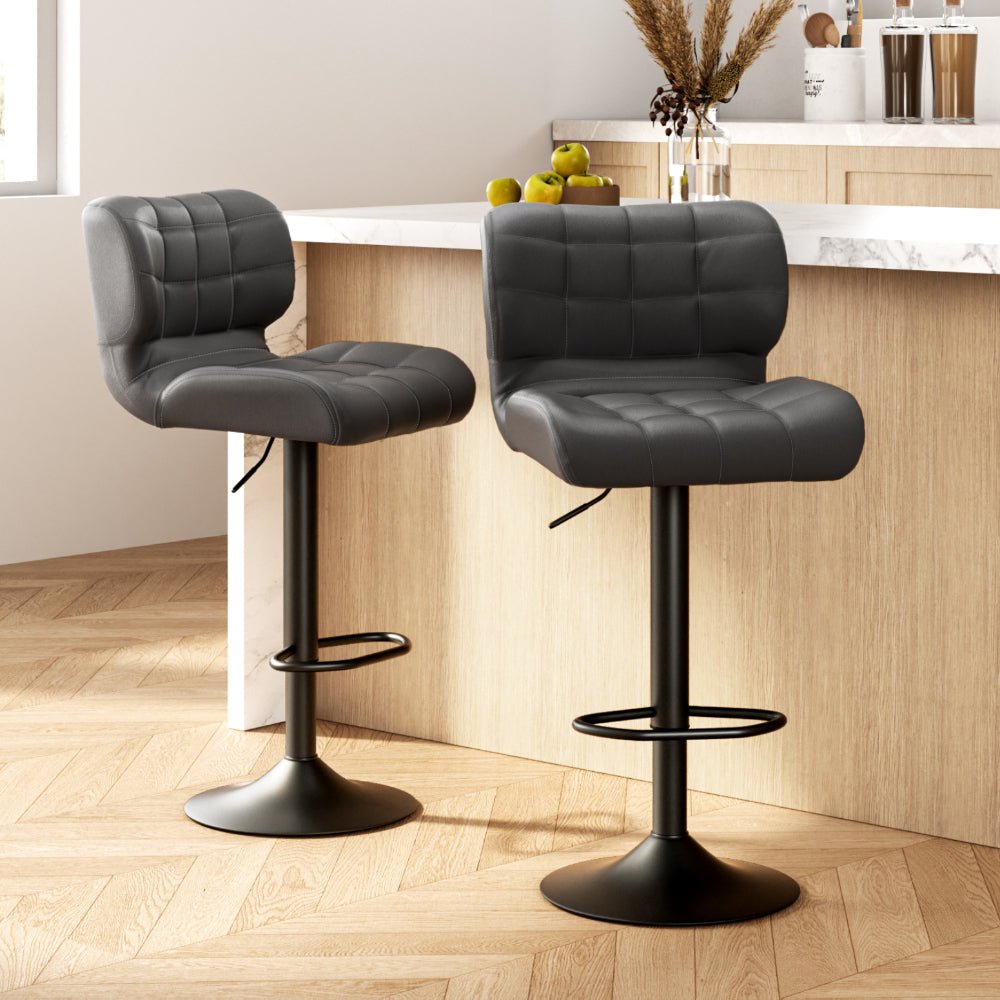 Two black bar stools with quilted seats in a kitchen setting.