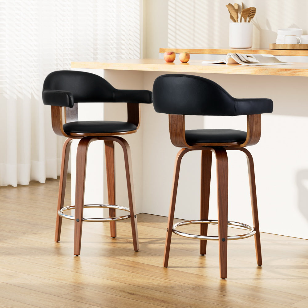 Two black bar stools with wooden legs in a kitchen setting.
