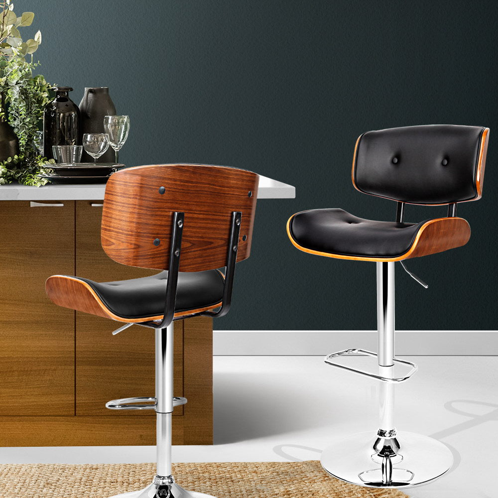 Two bar stools with wooden seats and black leather seats in a kitchen setting.