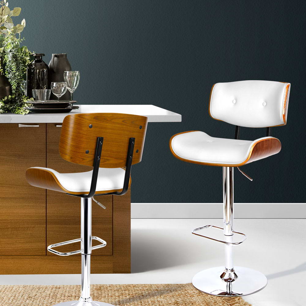 Two bar stools with wooden seats and white cushioned backs in a kitchen setting.