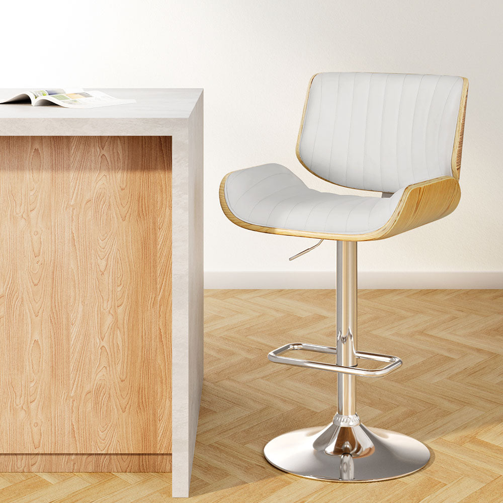 Modern bar stool with white cushioned seat and wooden frame next to a wooden counter.