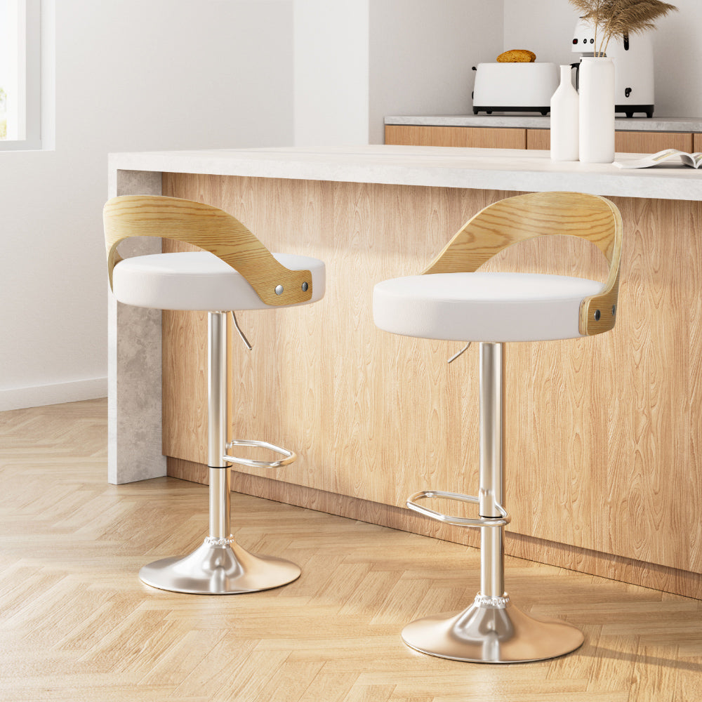 Two wooden bar stools with white seats in a kitchen setting.