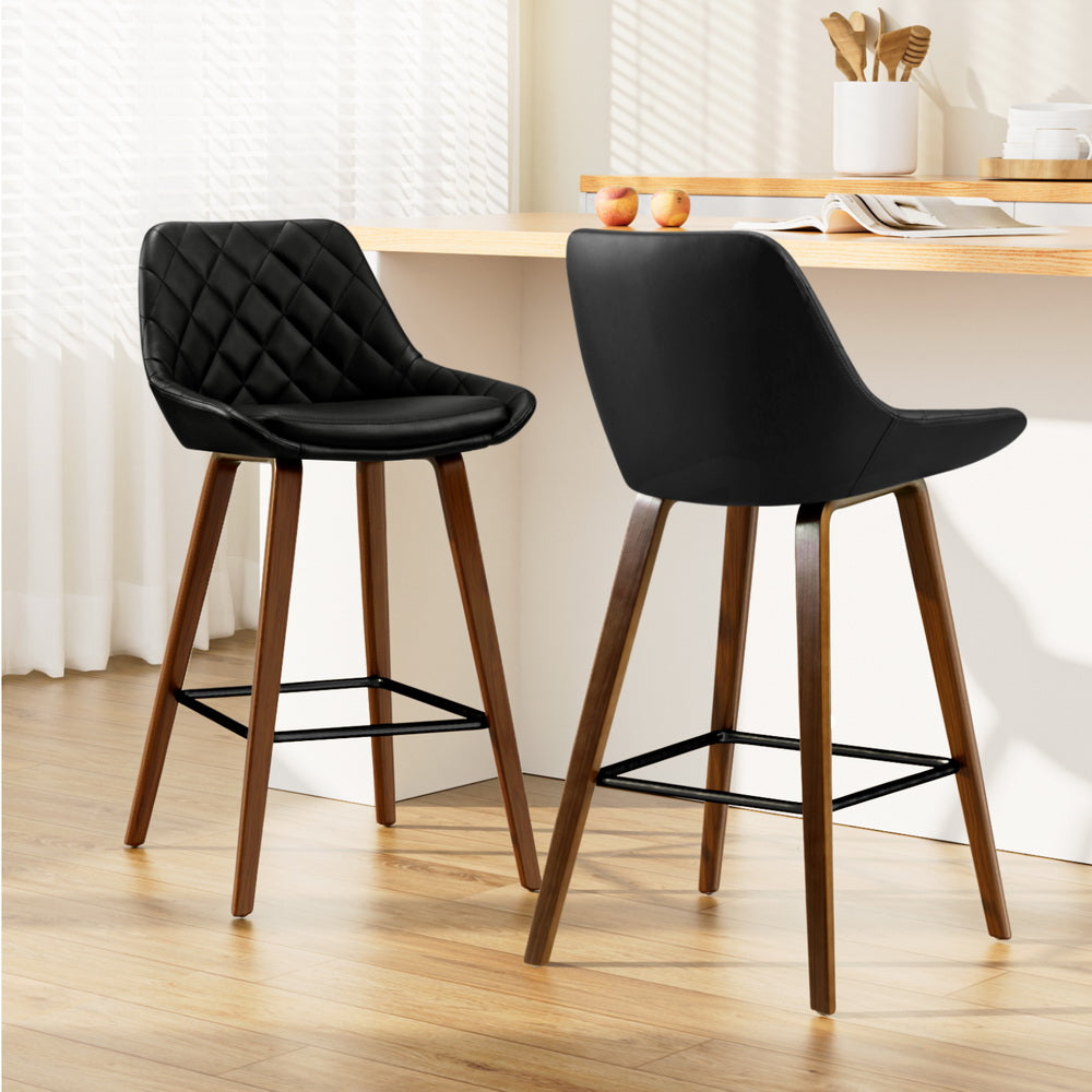 Two black bar stools with wooden legs in a kitchen setting.