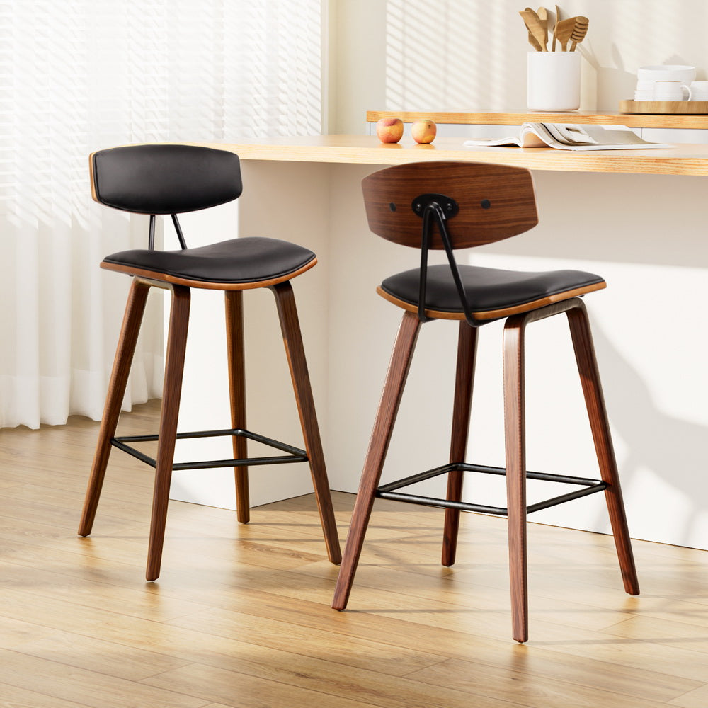Two wooden bar stools with black seats in a kitchen setting.