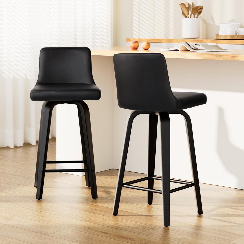 Two black bar stools in a kitchen setting with a wooden table and white walls.