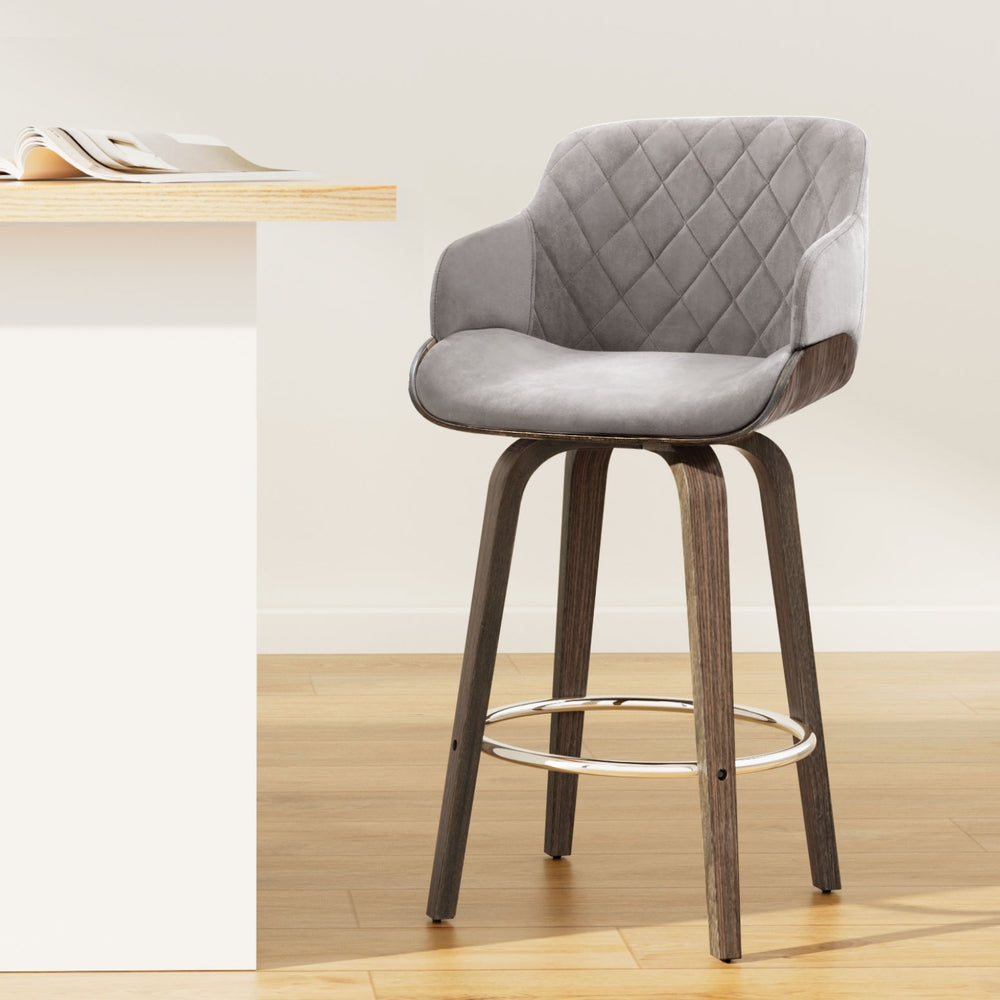 Gray quilted bar stool with wooden legs on a light wood floor.