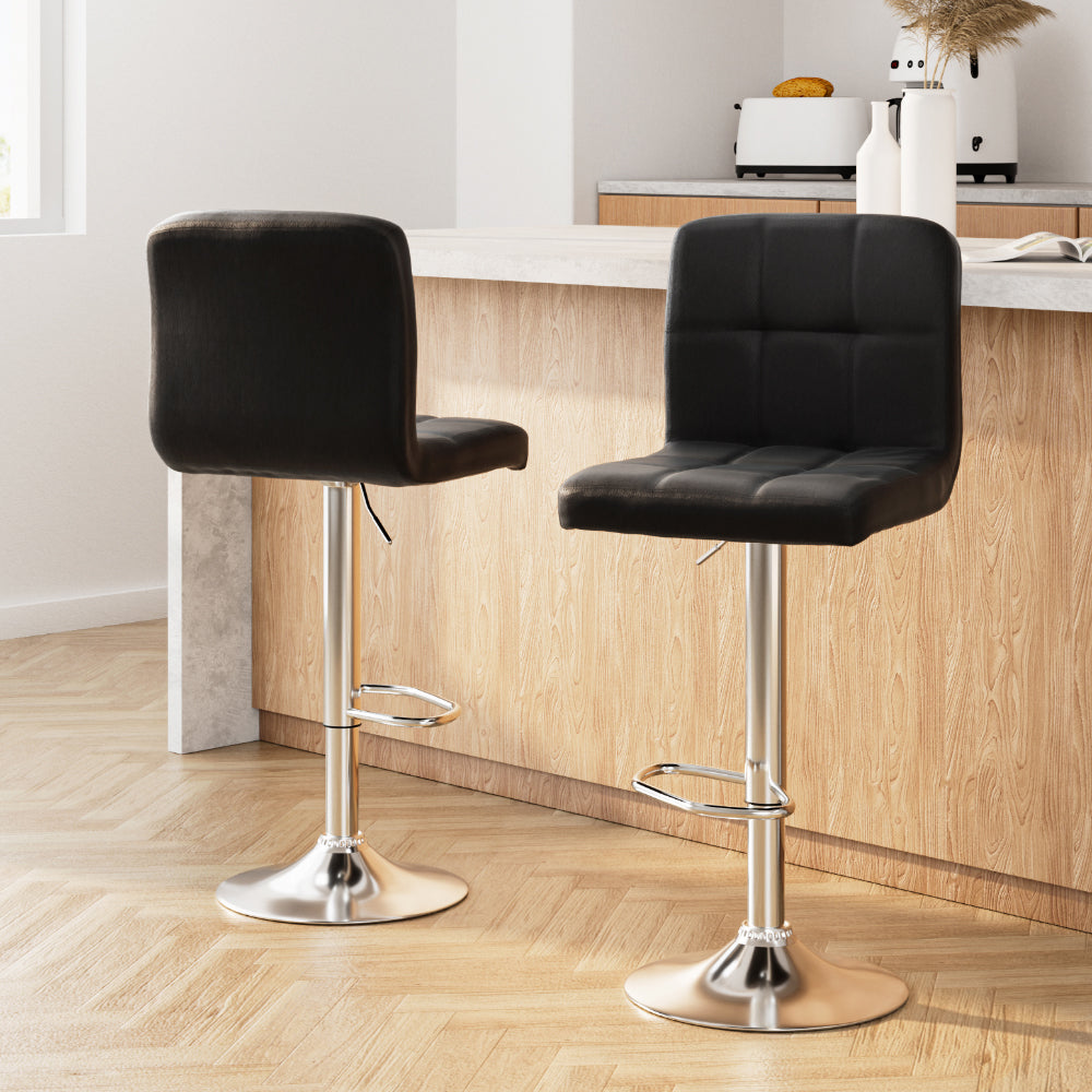 Two black bar stools with chrome bases in a kitchen setting.