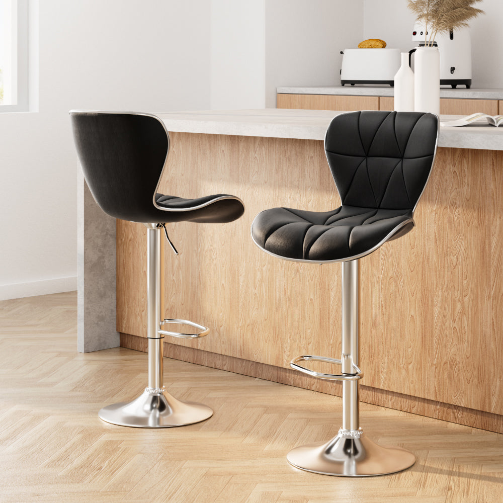 Two black bar stools with chrome bases in a kitchen setting.
