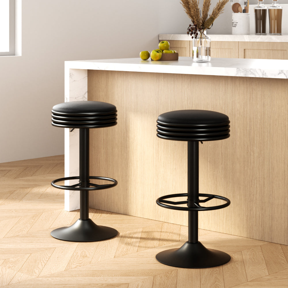 Two black bar stools in a kitchen setting with a counter and decor items.