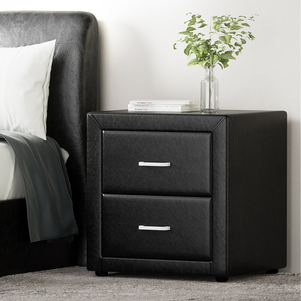 Black nightstand with two drawers next to a bed with gray bedding.