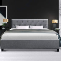 Gray upholstered bed with white bedding in a bedroom setting.