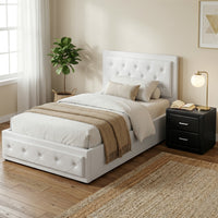 White upholstered bed with beige blanket in a bedroom setting.