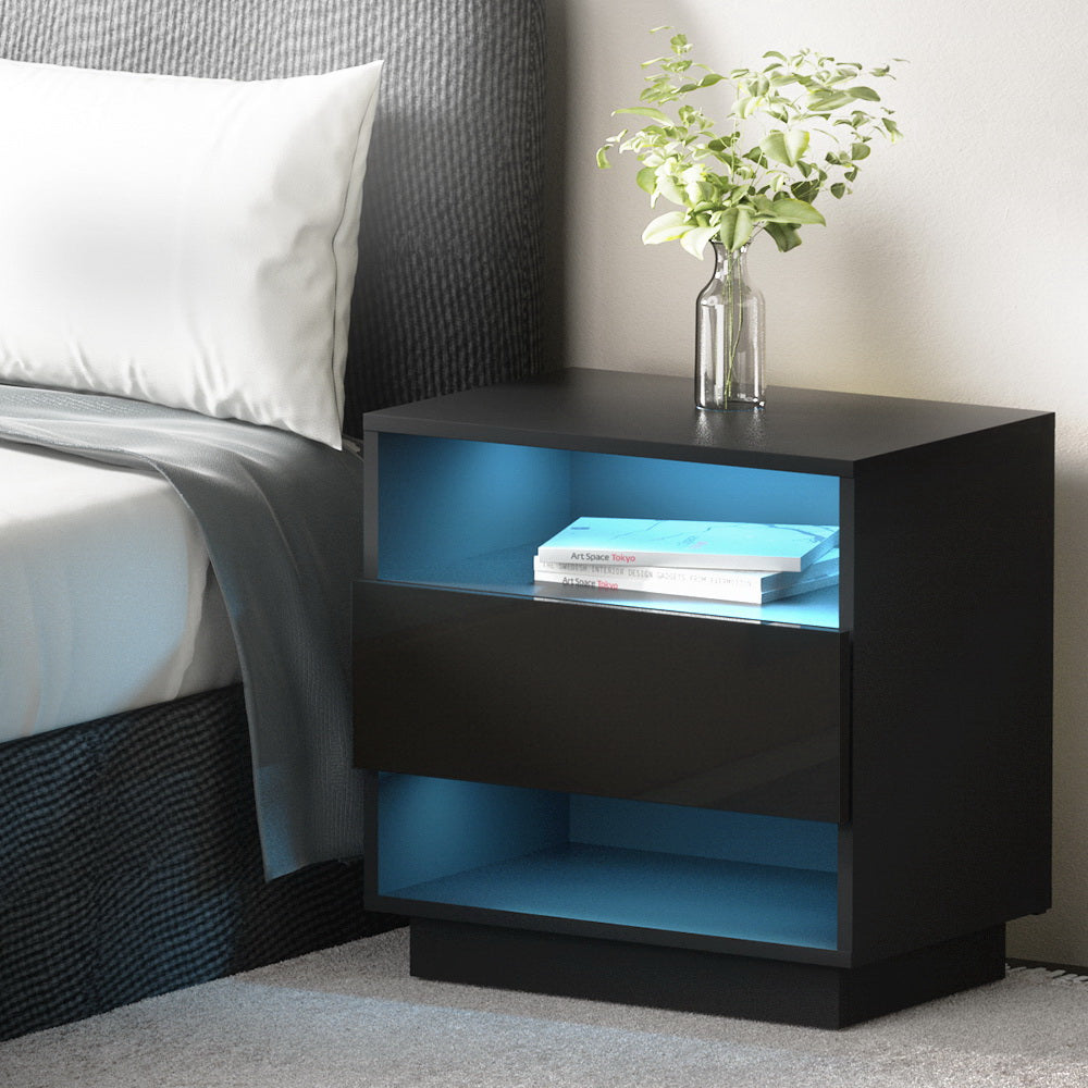 Black nightstand with blue LED lighting next to a bed