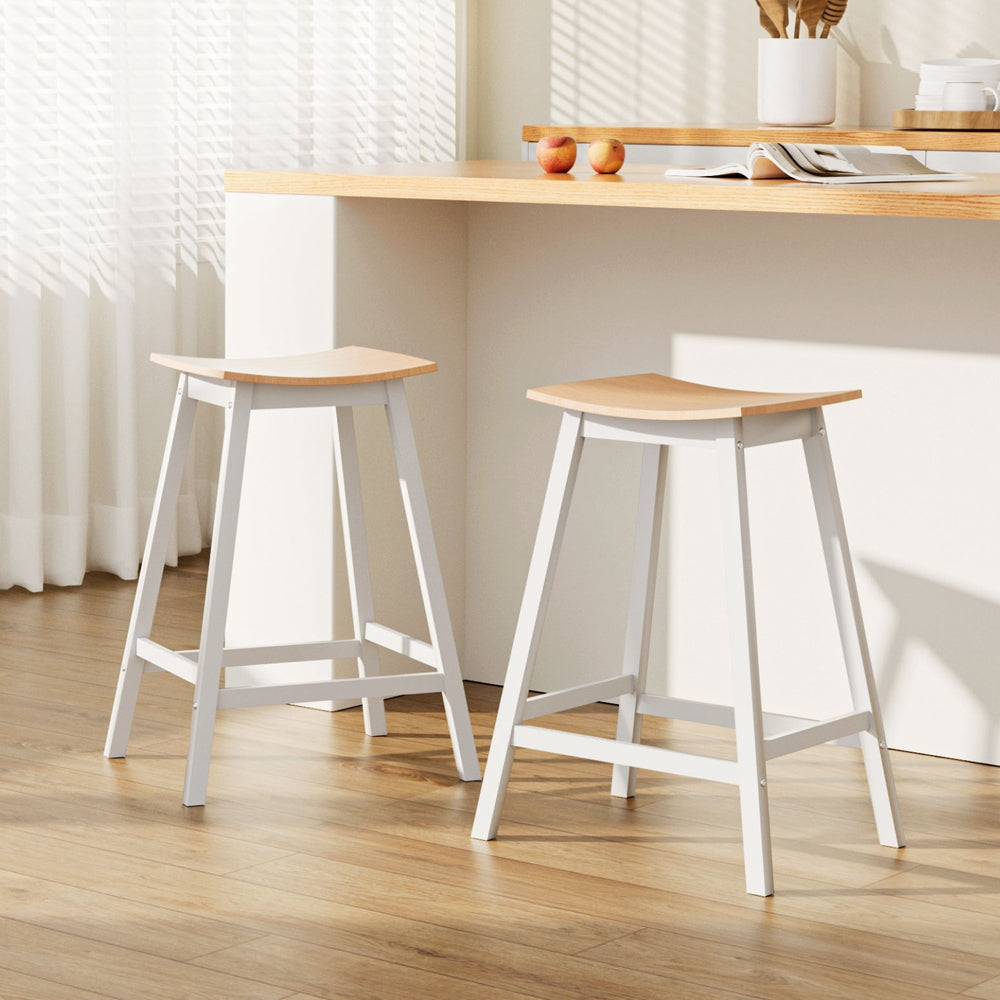 Two wooden stools with white legs in a room with a table and decor.