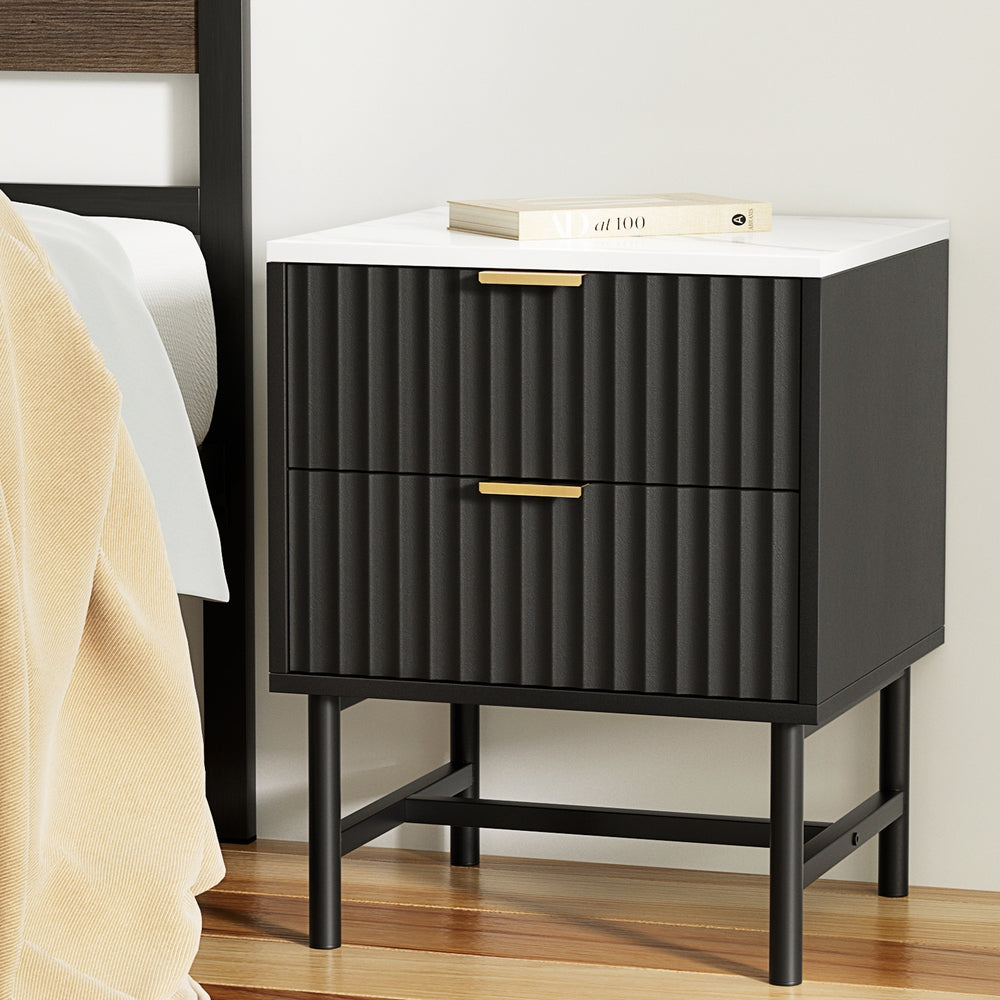 Black nightstand with white top next to a bed
