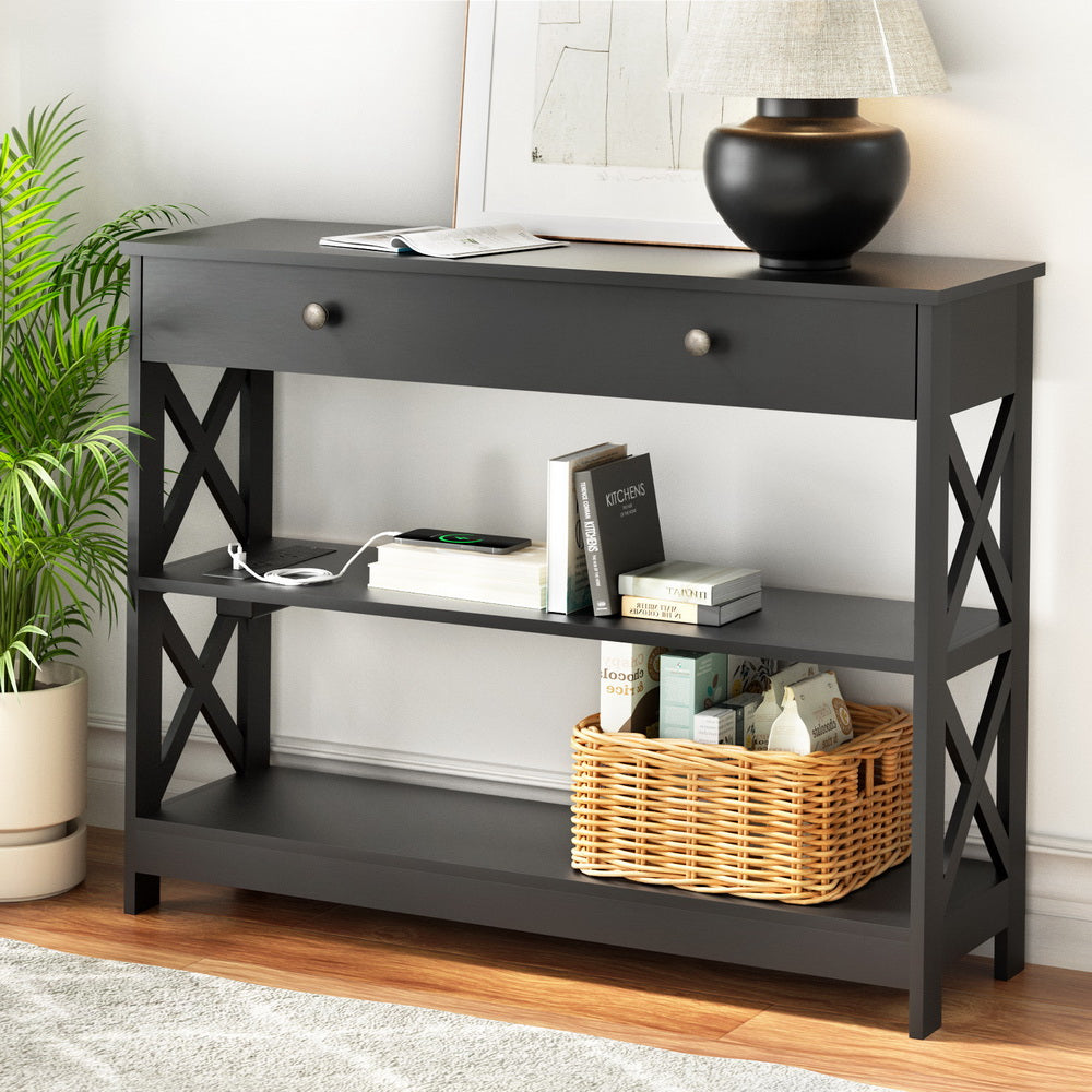Black console table with a basket, books, and a lamp in a room setting.