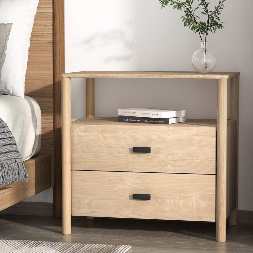 Wooden nightstand with two drawers next to a bed, featuring books and a plant.