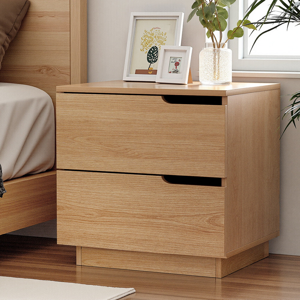 Wooden nightstand with two drawers in a bedroom setting.
