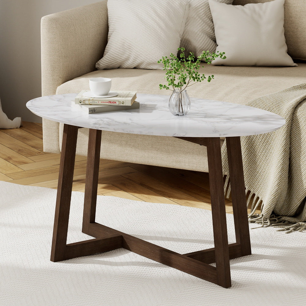 Coffee table with marble top and wooden legs in a living room setting.