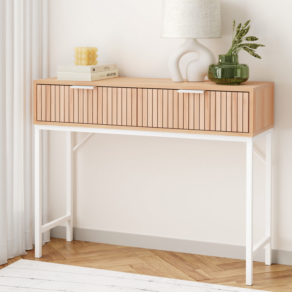 Wooden console table with white legs against a white wall
