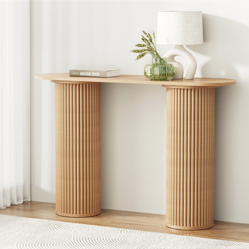 Wooden console table with decorative items against a white wall
