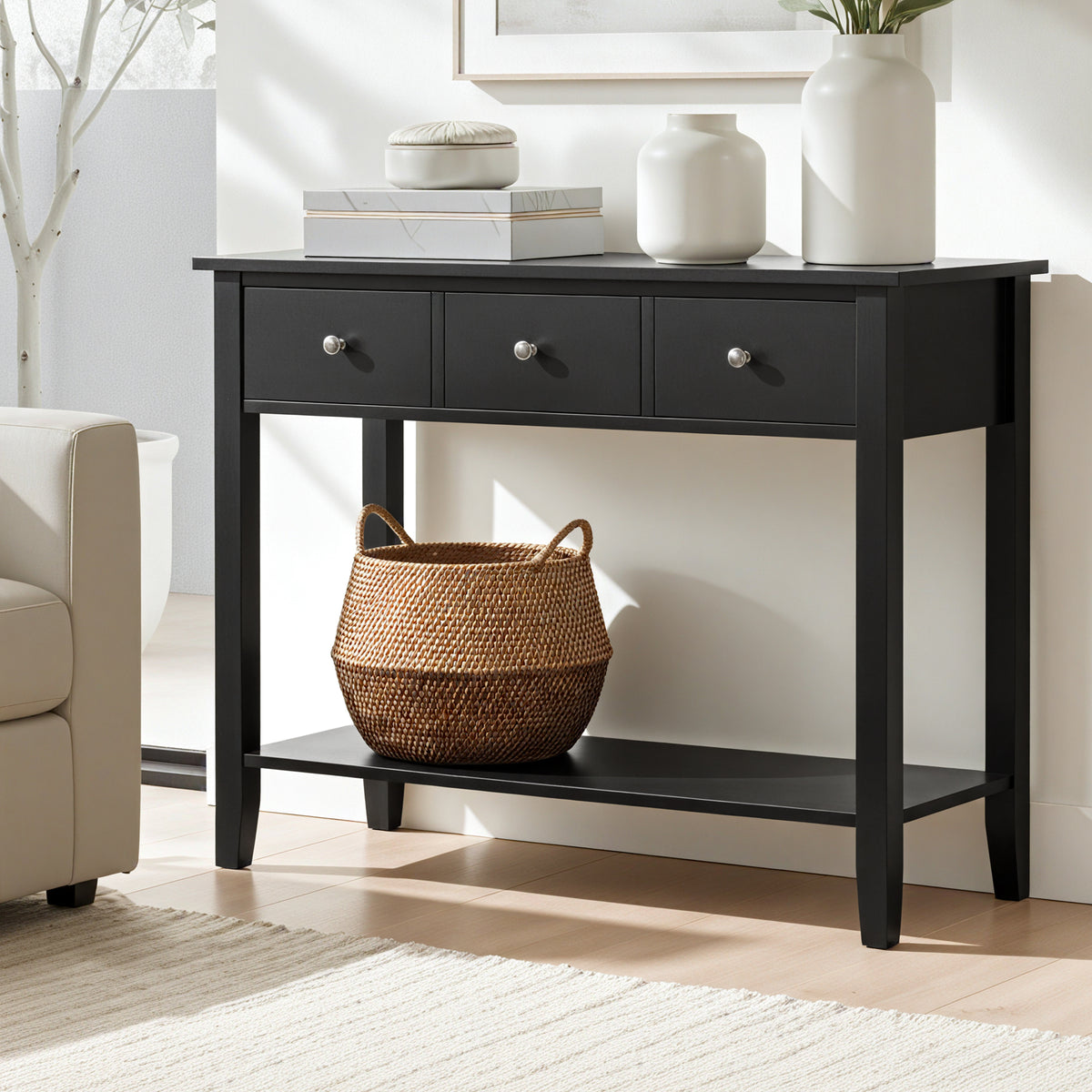 Black console table with drawers and a shelf in a living room setting.