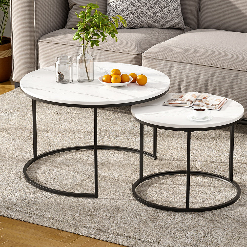 Two round coffee tables with marble top and black metal frame in a living room setting.