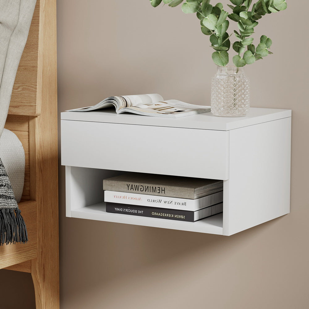 White wall-mounted shelf with books and a plant against a beige wall