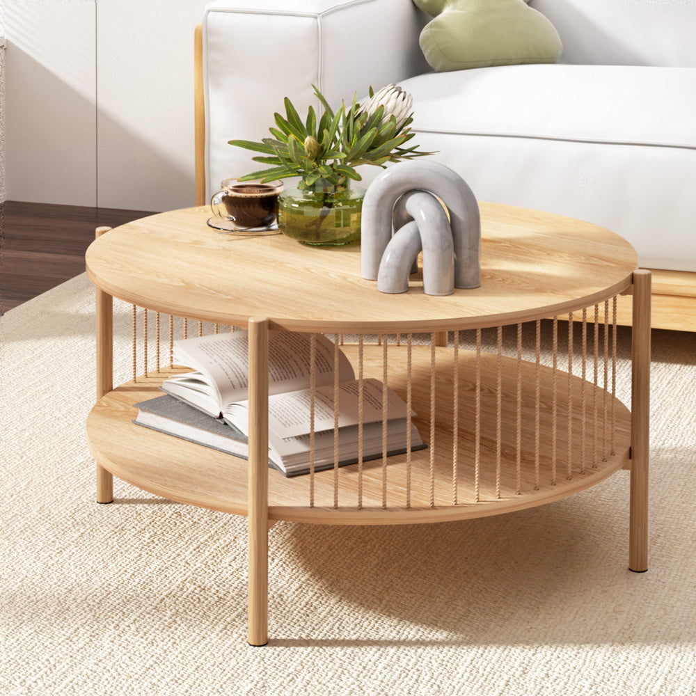 Round wooden coffee table with books, a plant, and decorative items in a living room setting.