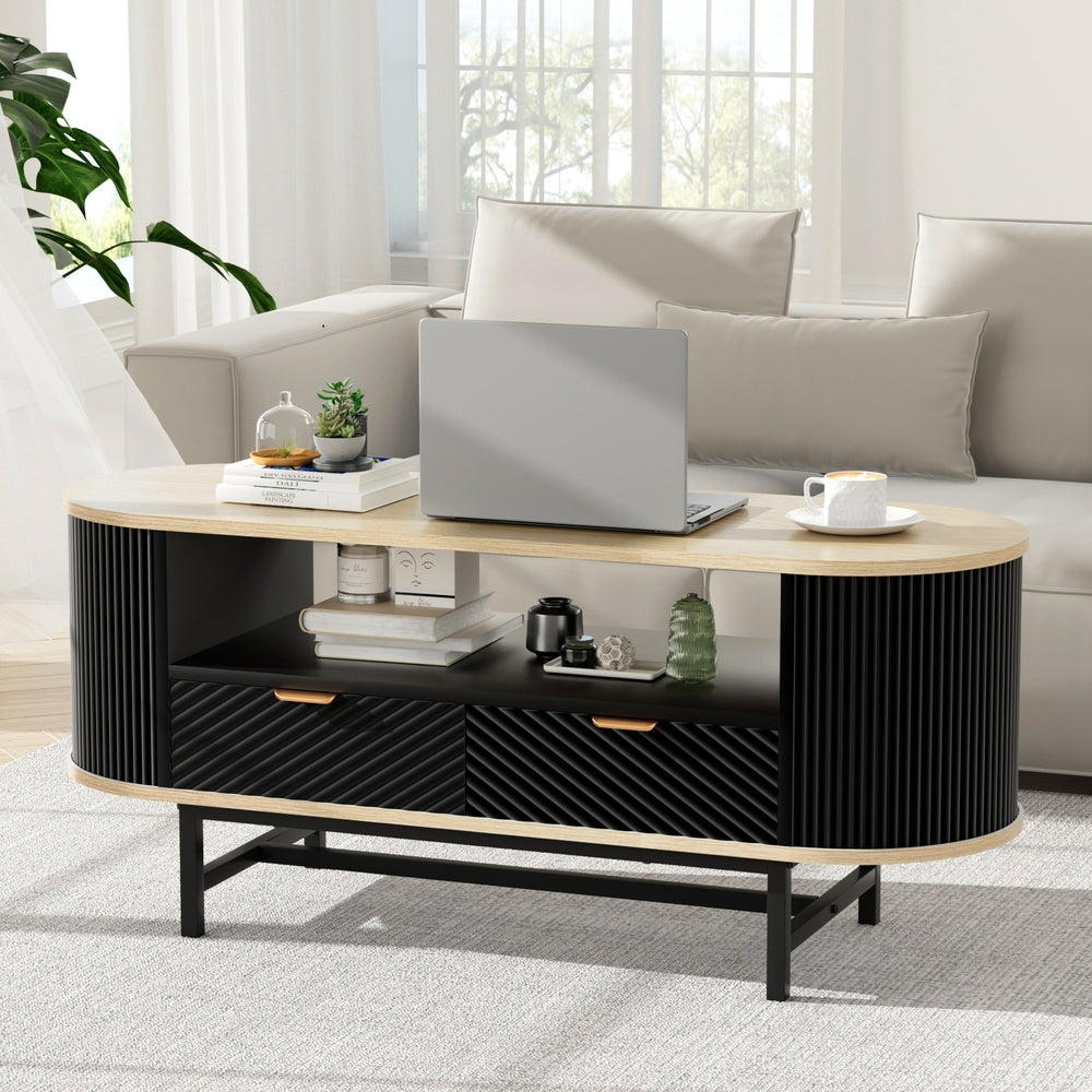 Modern coffee table with a laptop, books, and decorative items in a living room setting.