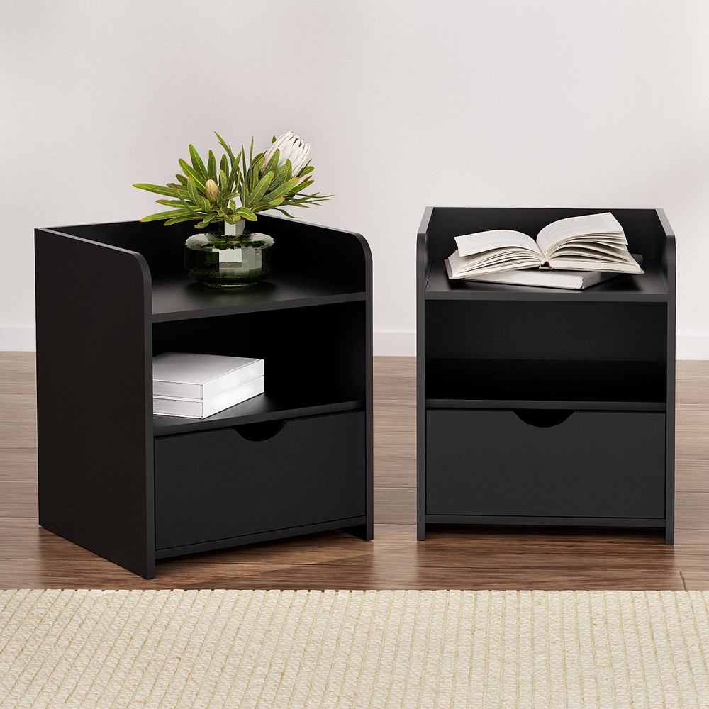 Two black nightstands with books and a plant on a wooden floor.