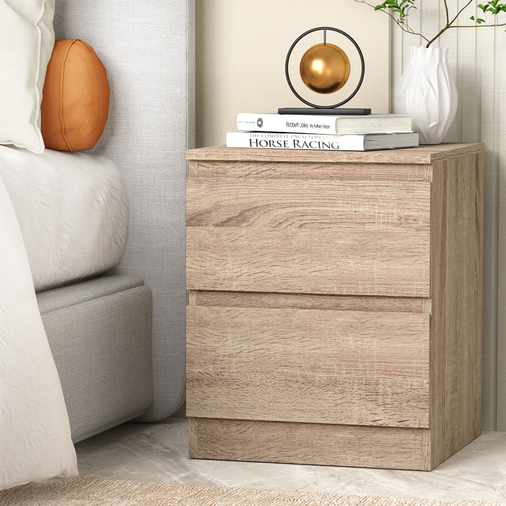 Wooden nightstand with decorative items next to a bed in a bedroom setting