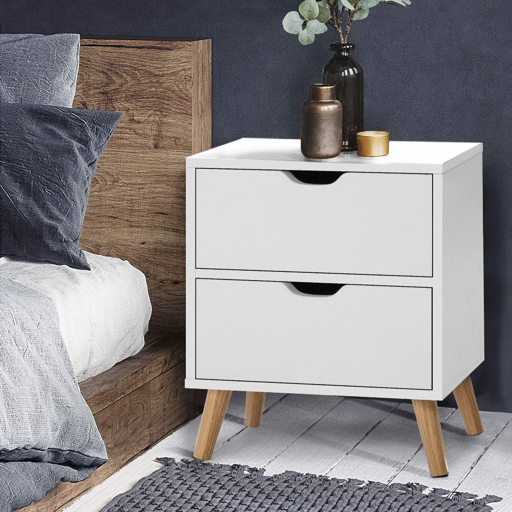 White nightstand with two drawers next to a bed with wooden headboard