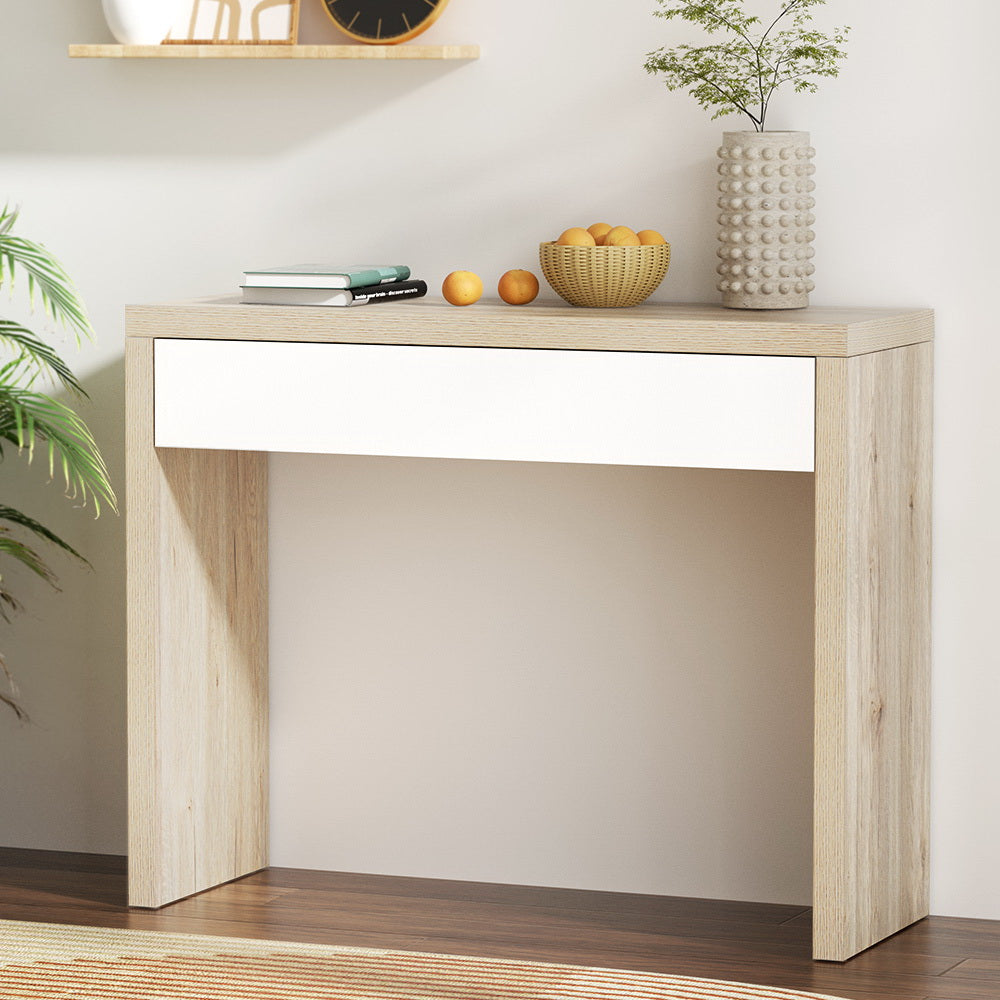 Light wood console table with decorative items against a white wall