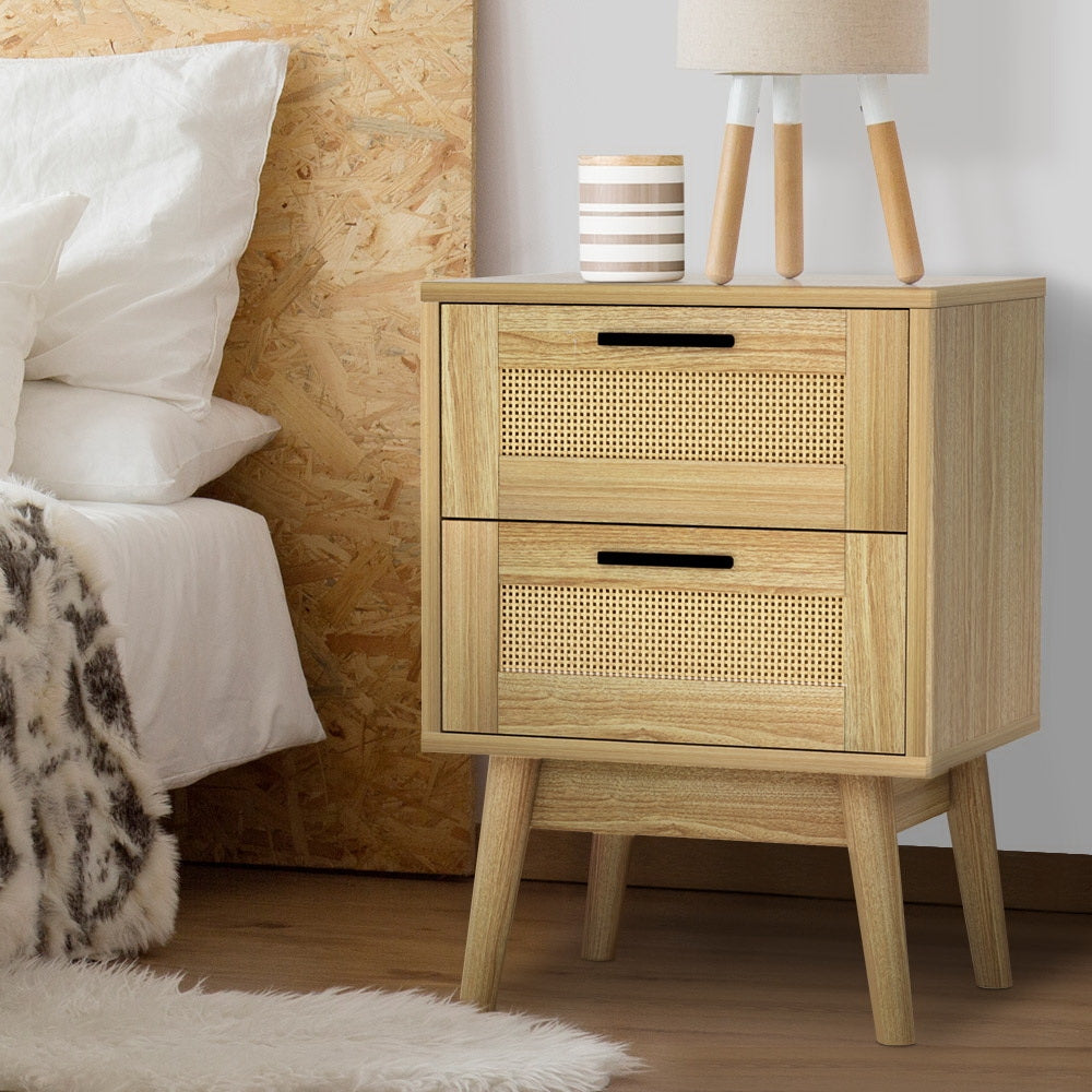 Wooden nightstand with two drawers next to a bed with white bedding.