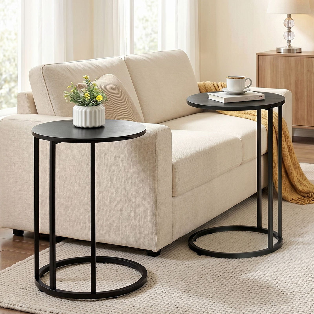 Two black side tables in a living room setting with a beige sofa.