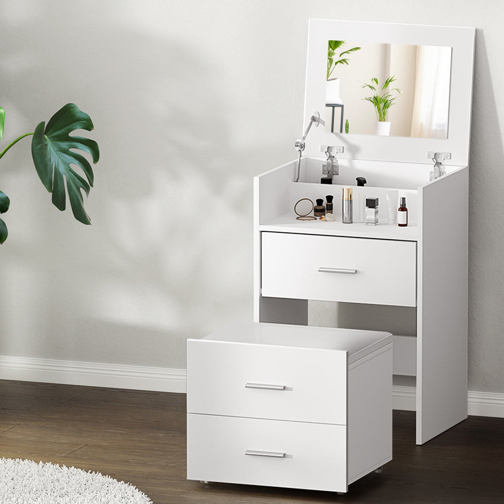 White vanity unit with mirror and drawers in a room with a plant and rug.