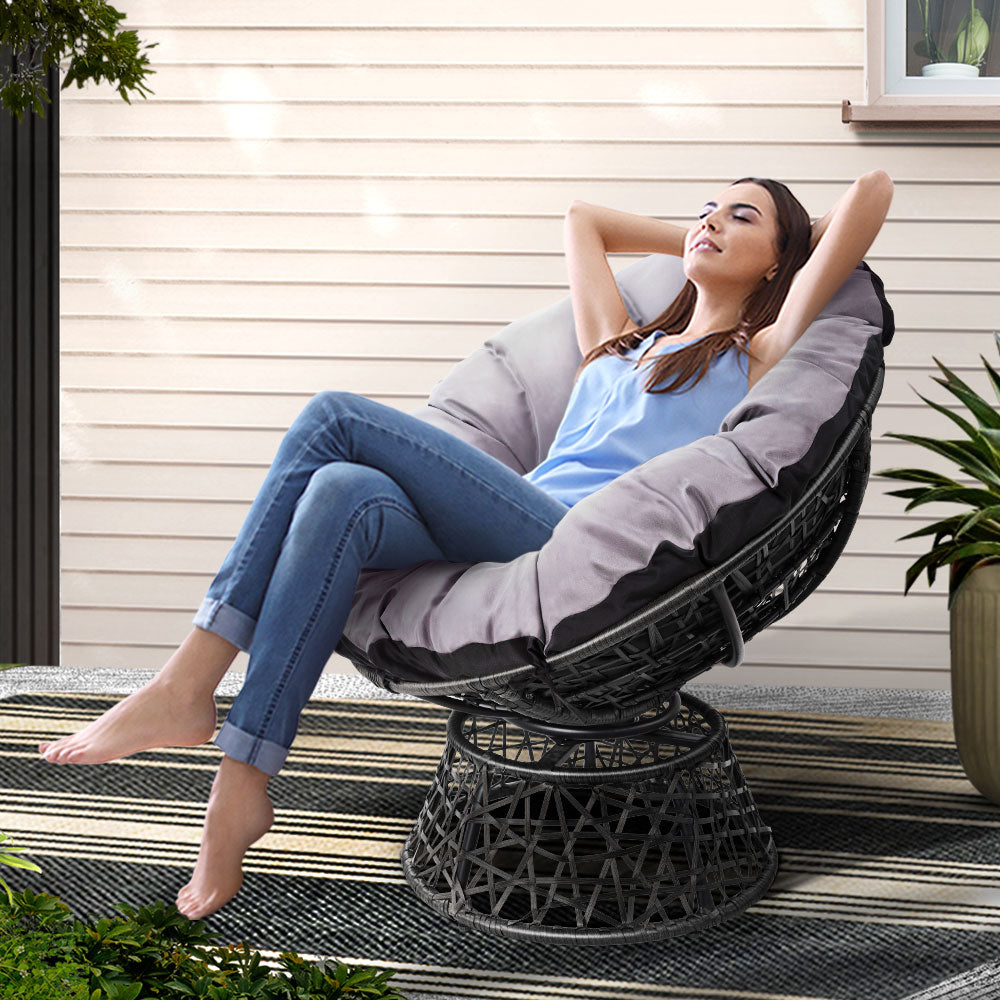 Fernand Outdoor Papasan Chair | Black with a woman relaxing outdoors on a stylish wicker seat.