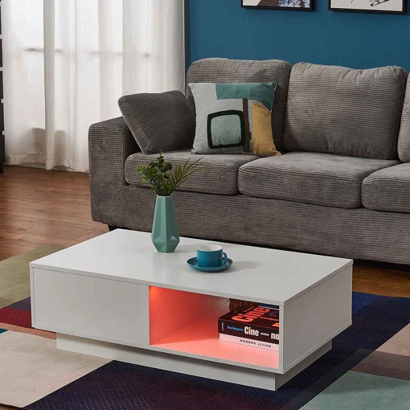 Gray sofa with colorful pillows and a white coffee table with a plant and cup in a living room.