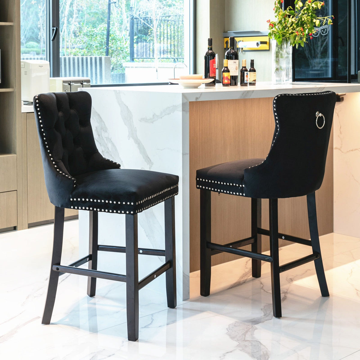 Two black bar stools with nailhead trim in a modern kitchen setting.