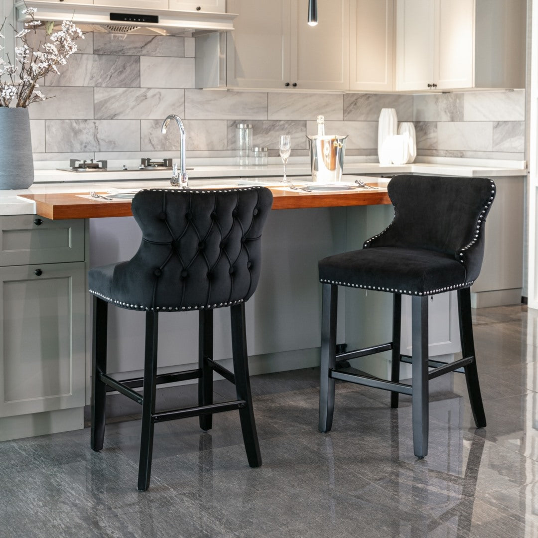 Two black bar stools with tufted seats in a modern kitchen.