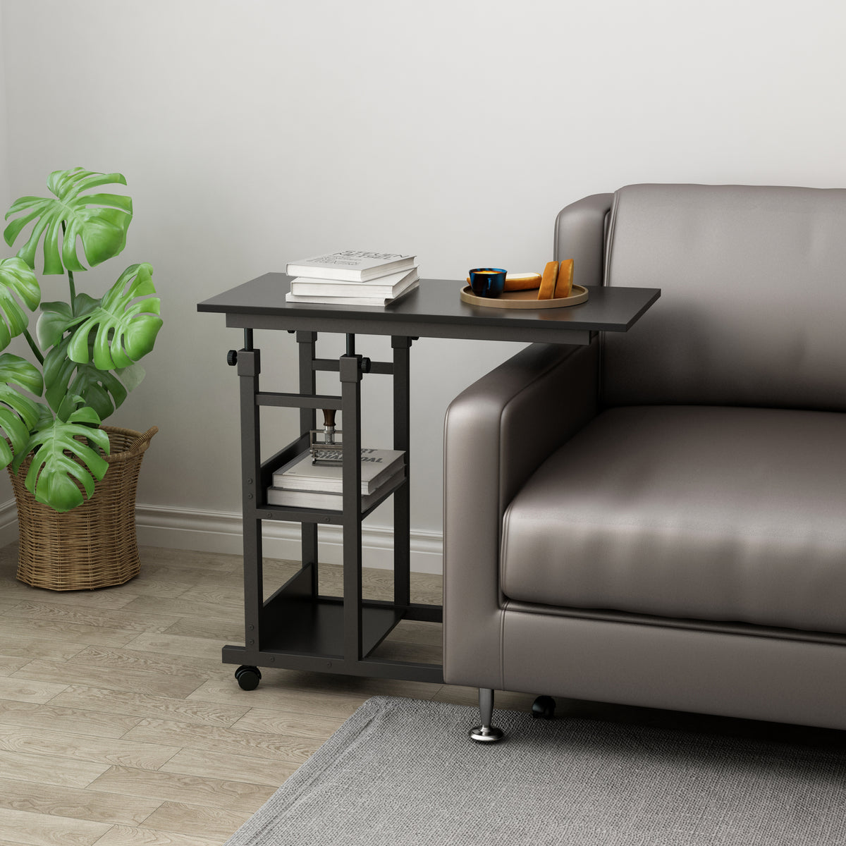 Black side table with books and a plant next to a gray sofa in a living room.